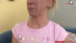 Blonde Frau mit Spermagesicht und weit geöffnetem Mund auf blauem Sofa